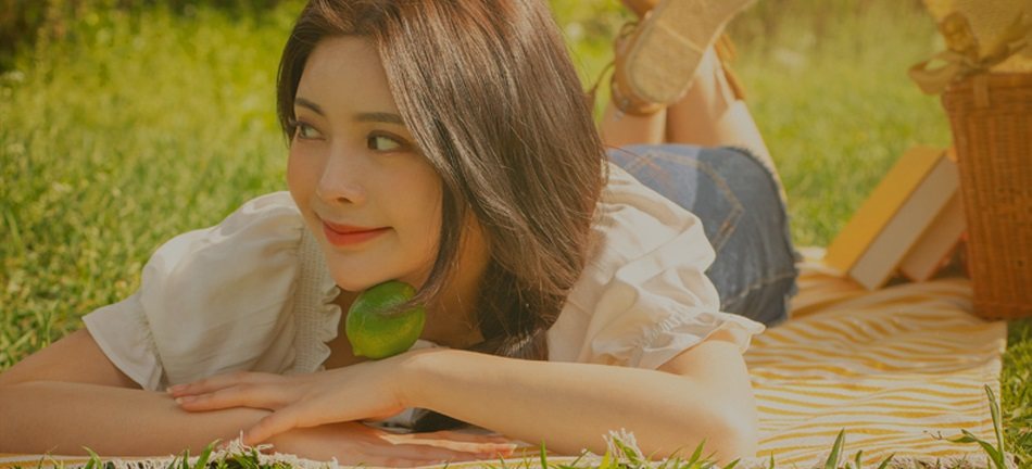 잔디밭 피크닉 매트에 엎드려 라임을 턱에 댄 여성 모델